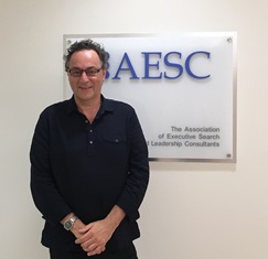 Gerd Leonhard dressed in a black button down stands in front of the white AESC sign